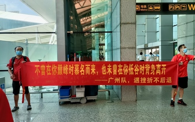 广州球迷机场迎接广州队,拉出“未曾在你低谷时背身离开”横幅